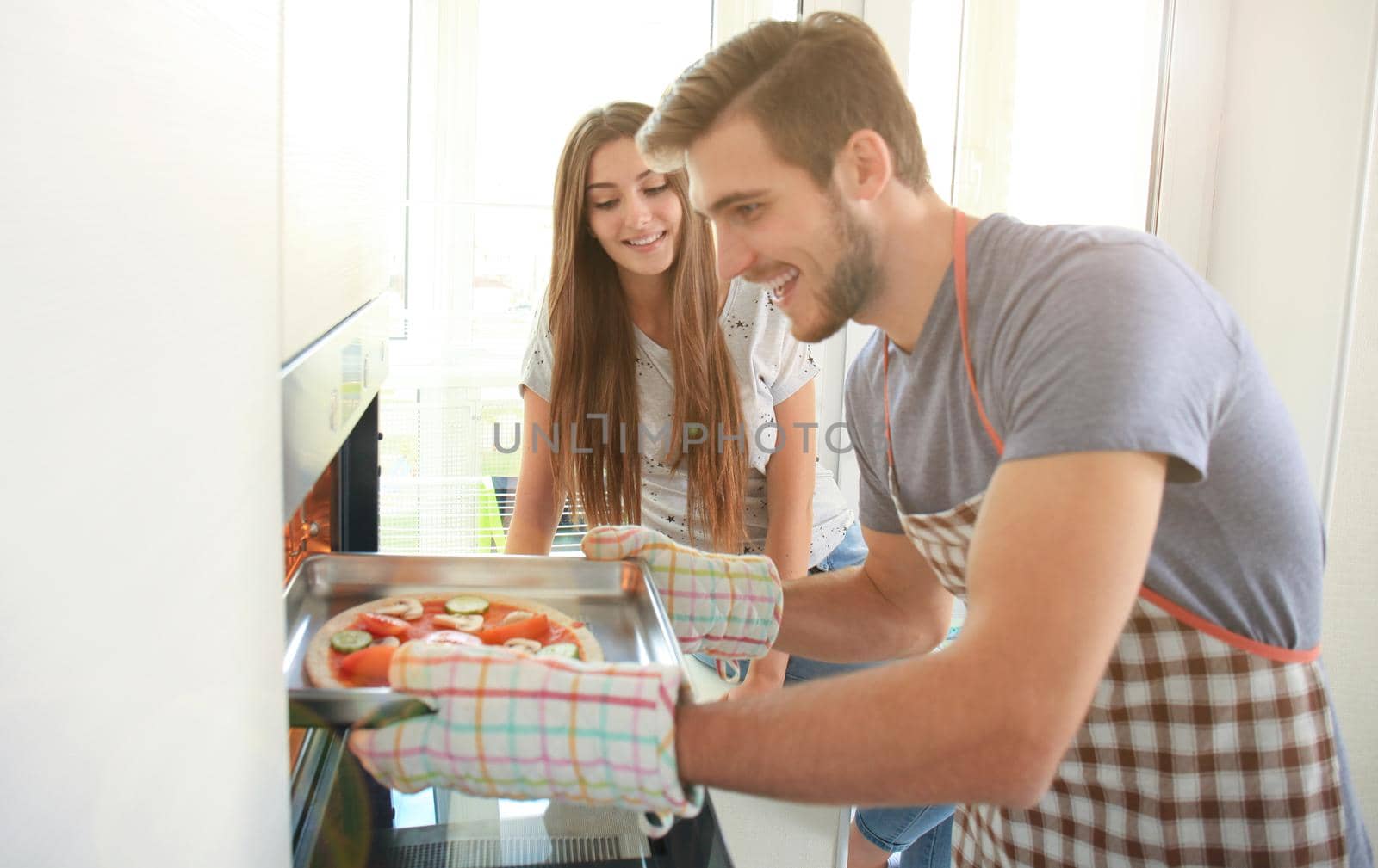 Young couple making pizza in kitchen together