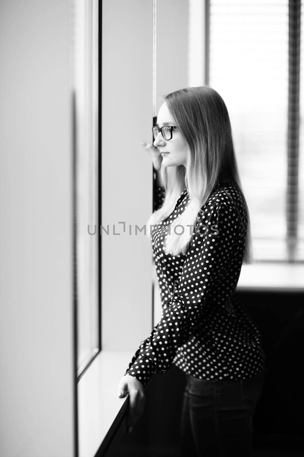 confident business woman standing near window in office