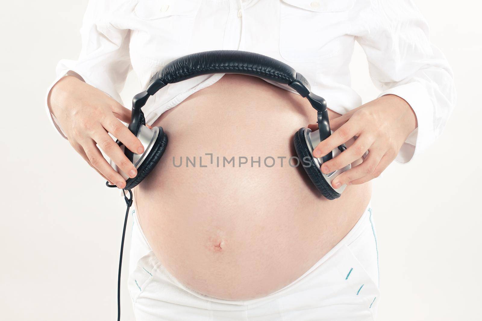 thoughtful pregnant woman gives an unborn child listen to music using headphones .isolated on a white background.