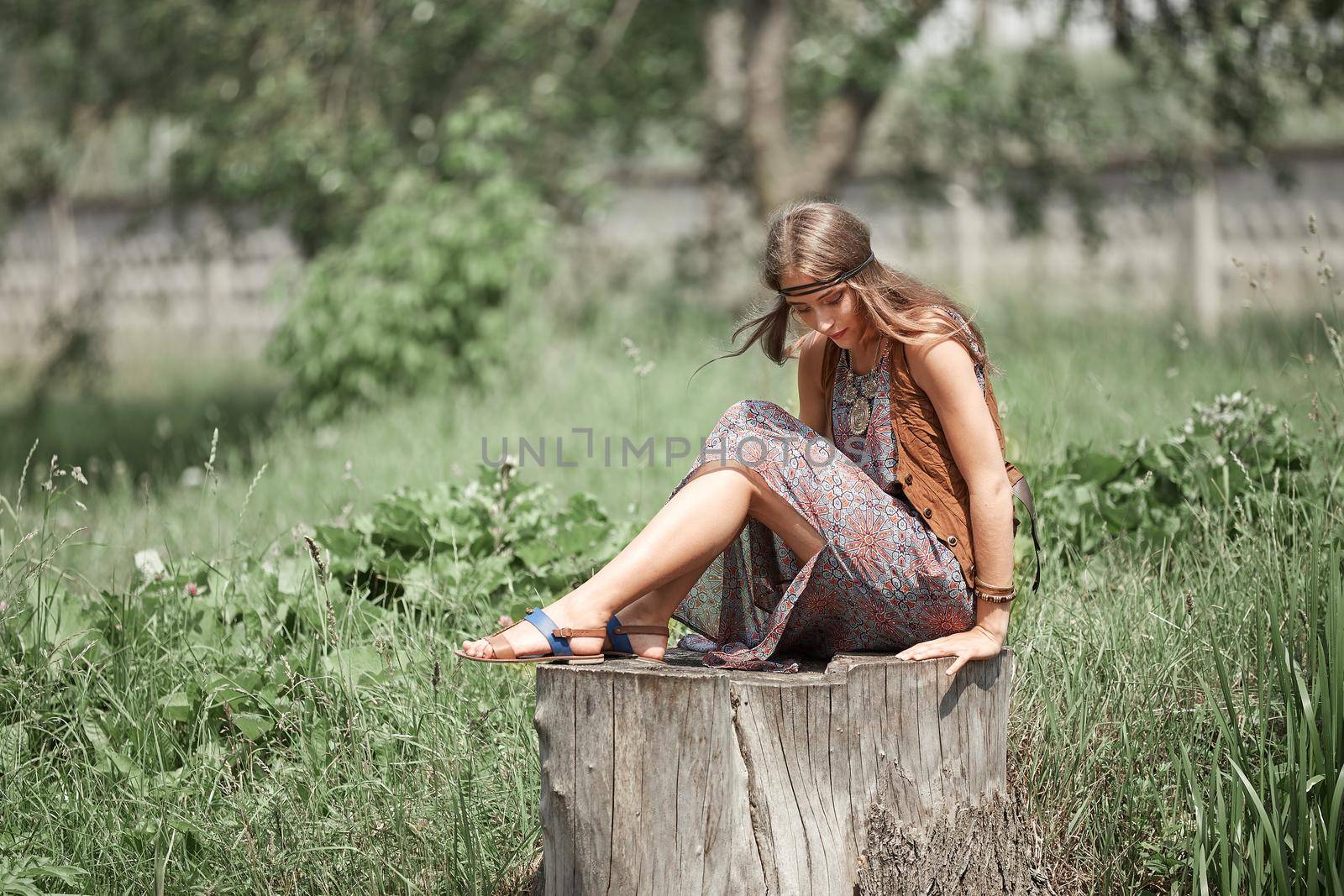 dreaming hippie girl sitting on a big stump in a city Park. the concept of unity with nature