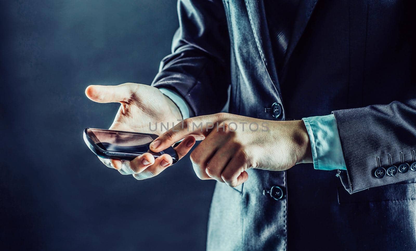 businessman presses a finger on the smartphone screen.photo on a black background and has space for your text.