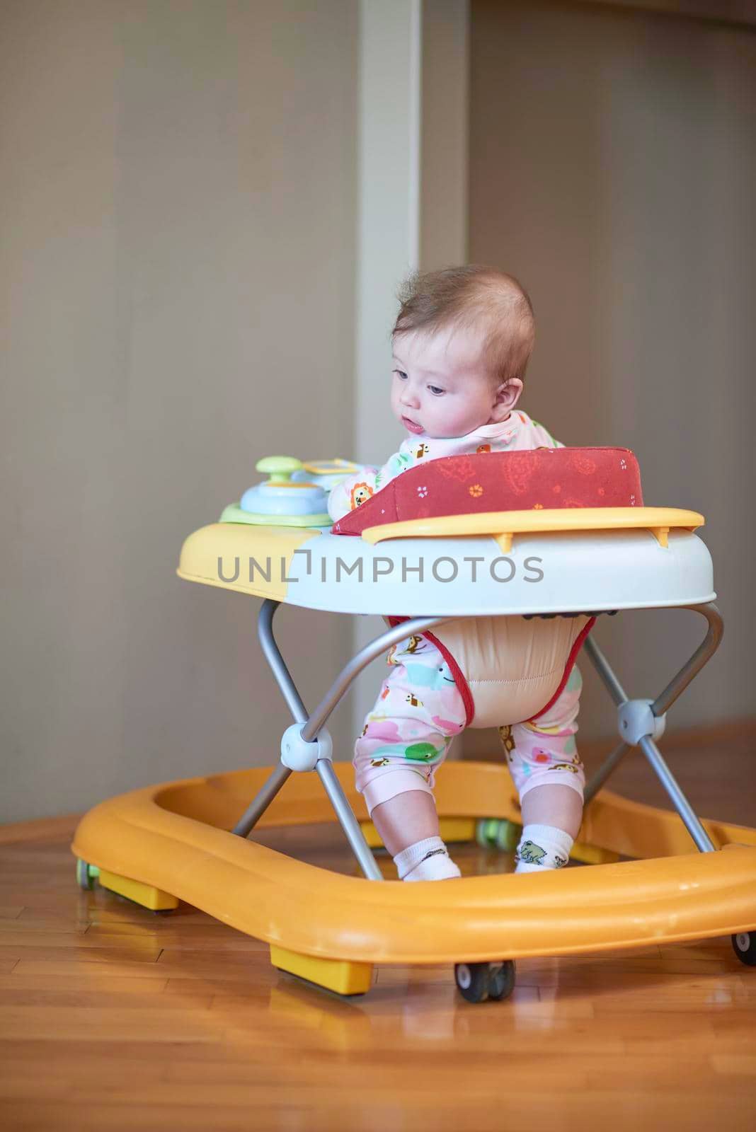 cute little baby learning to walk in walker at home