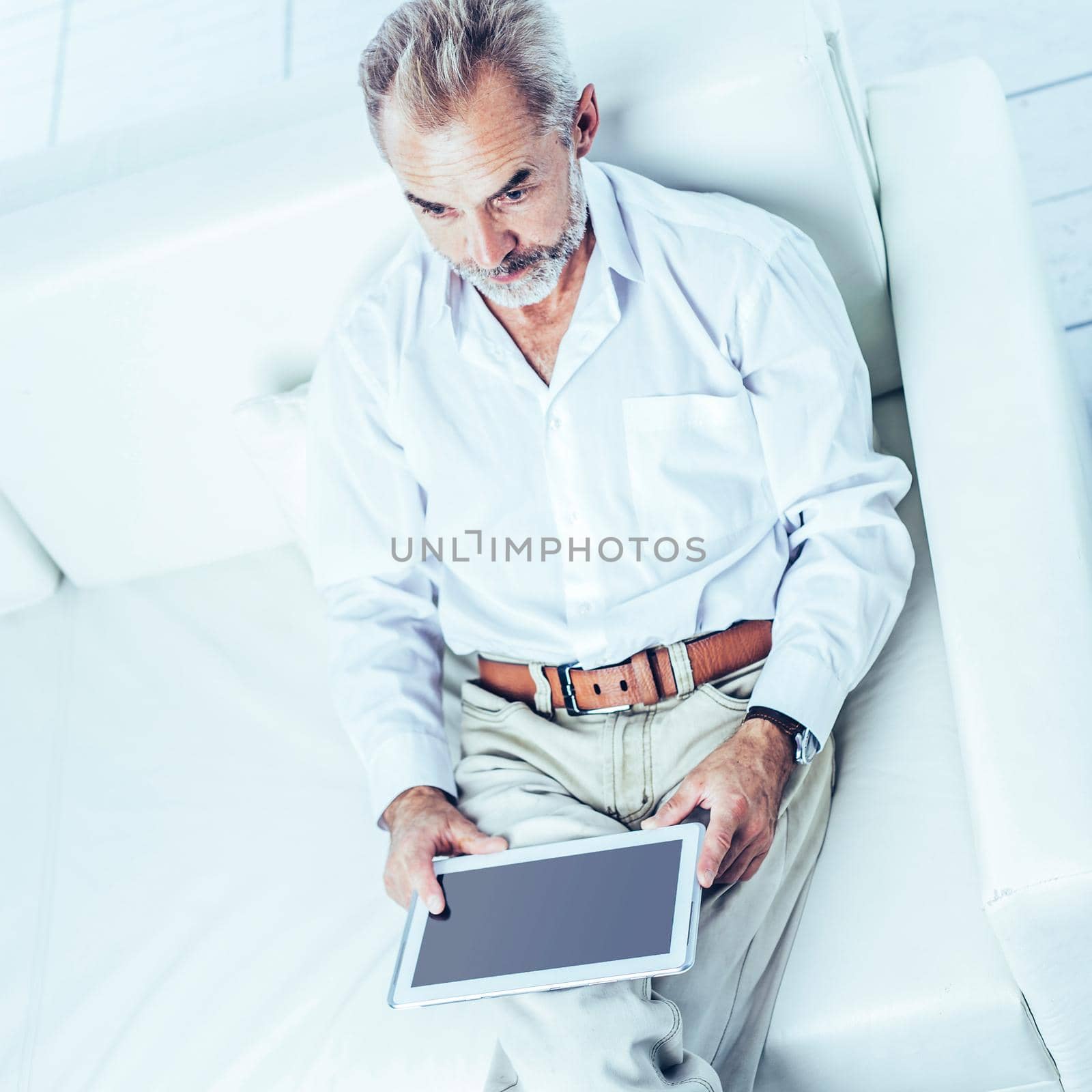 top view - a successful businessman with digital tablet sitting in modern office chair.