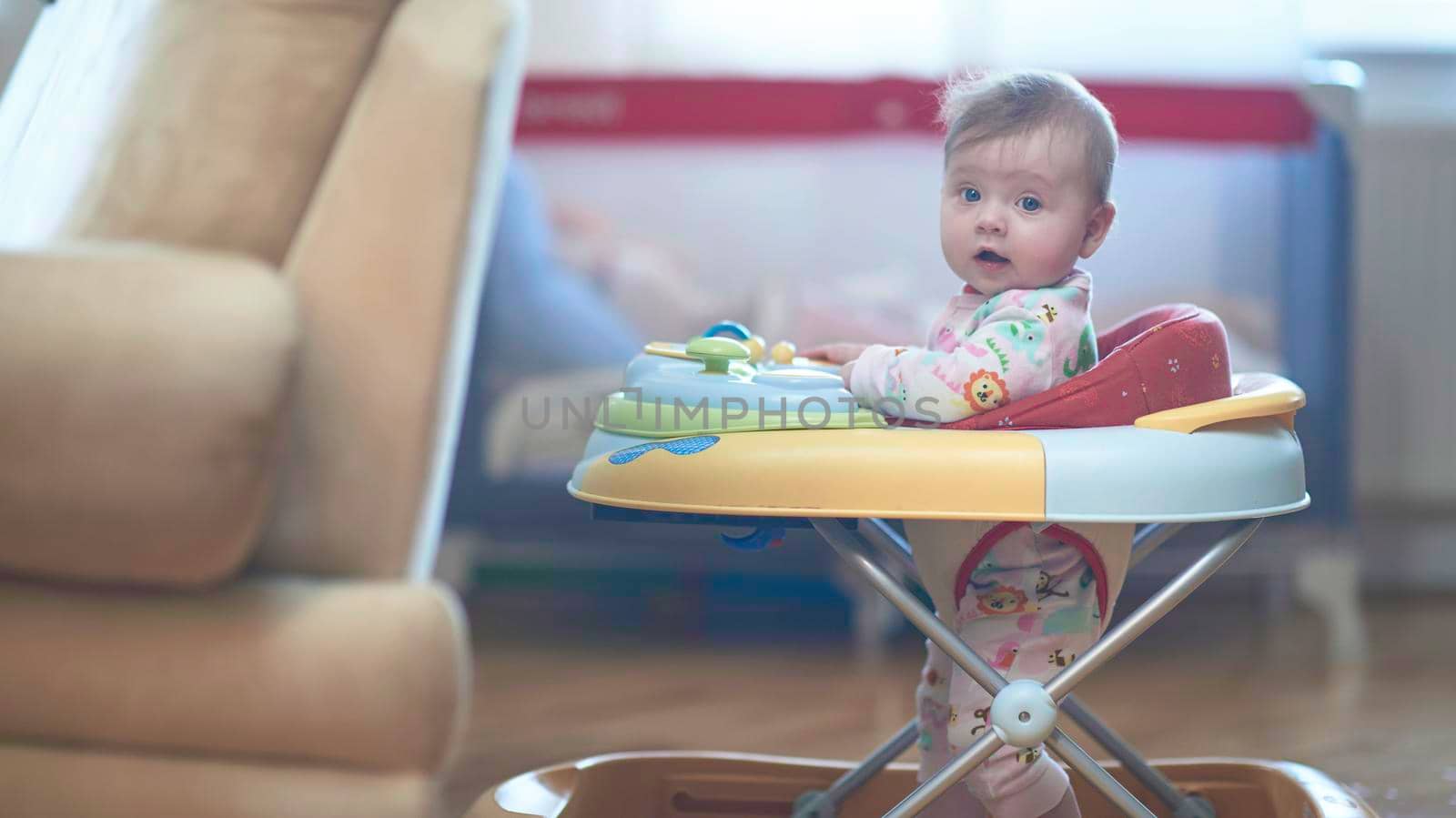 cute little baby learning to walk in walker at home