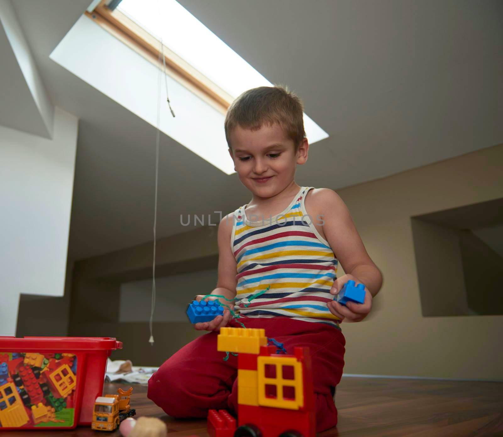 Little boy child playing with creative plastic toys indoor, building different cars and building  objects