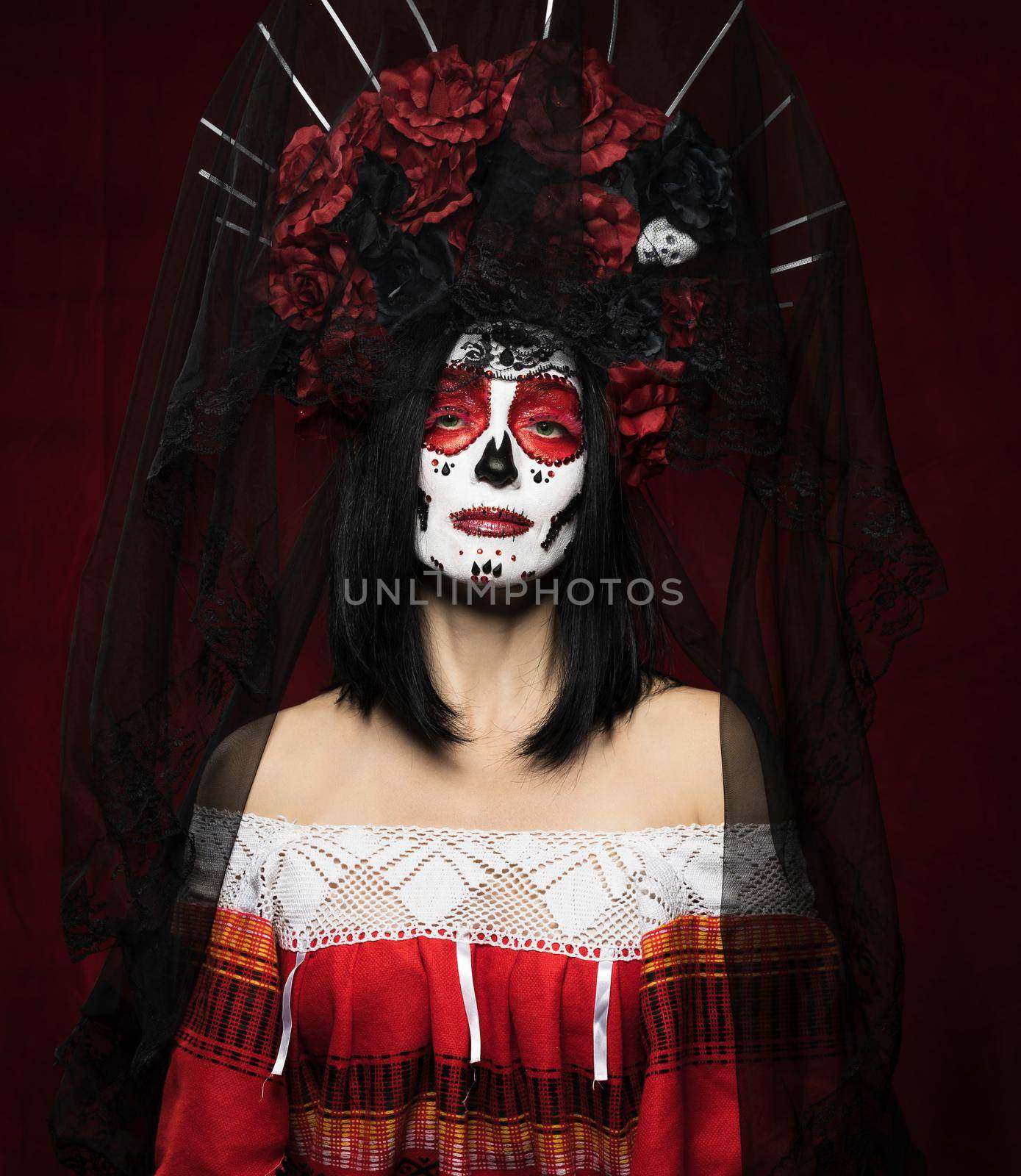 portrait of a beautiful woman with a sugar skull makeup with a wreath of flowers on her head, red background by ndanko