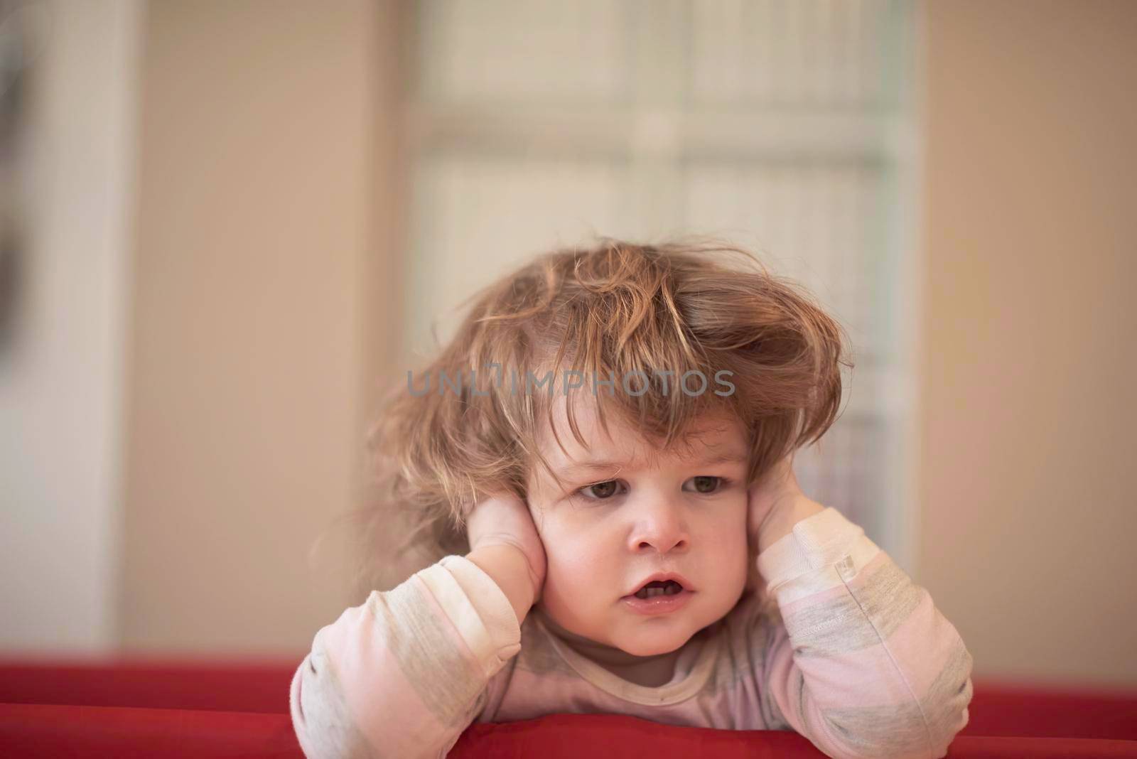 little baby girl with strange hairstyle and curlers in bed at home