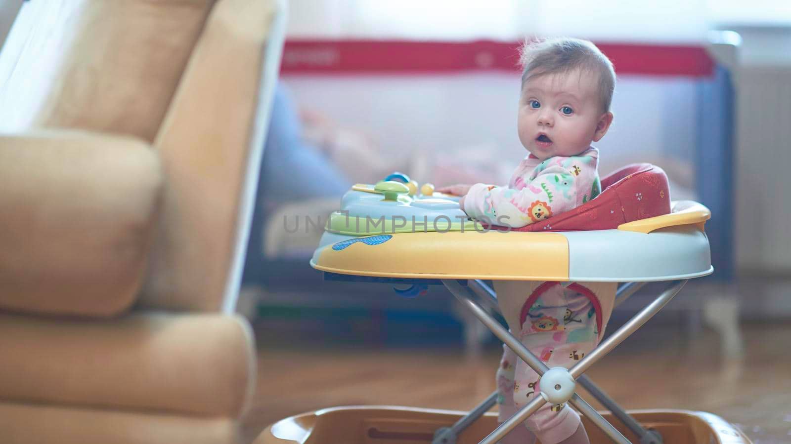 cute little baby learning to walk in walker at home