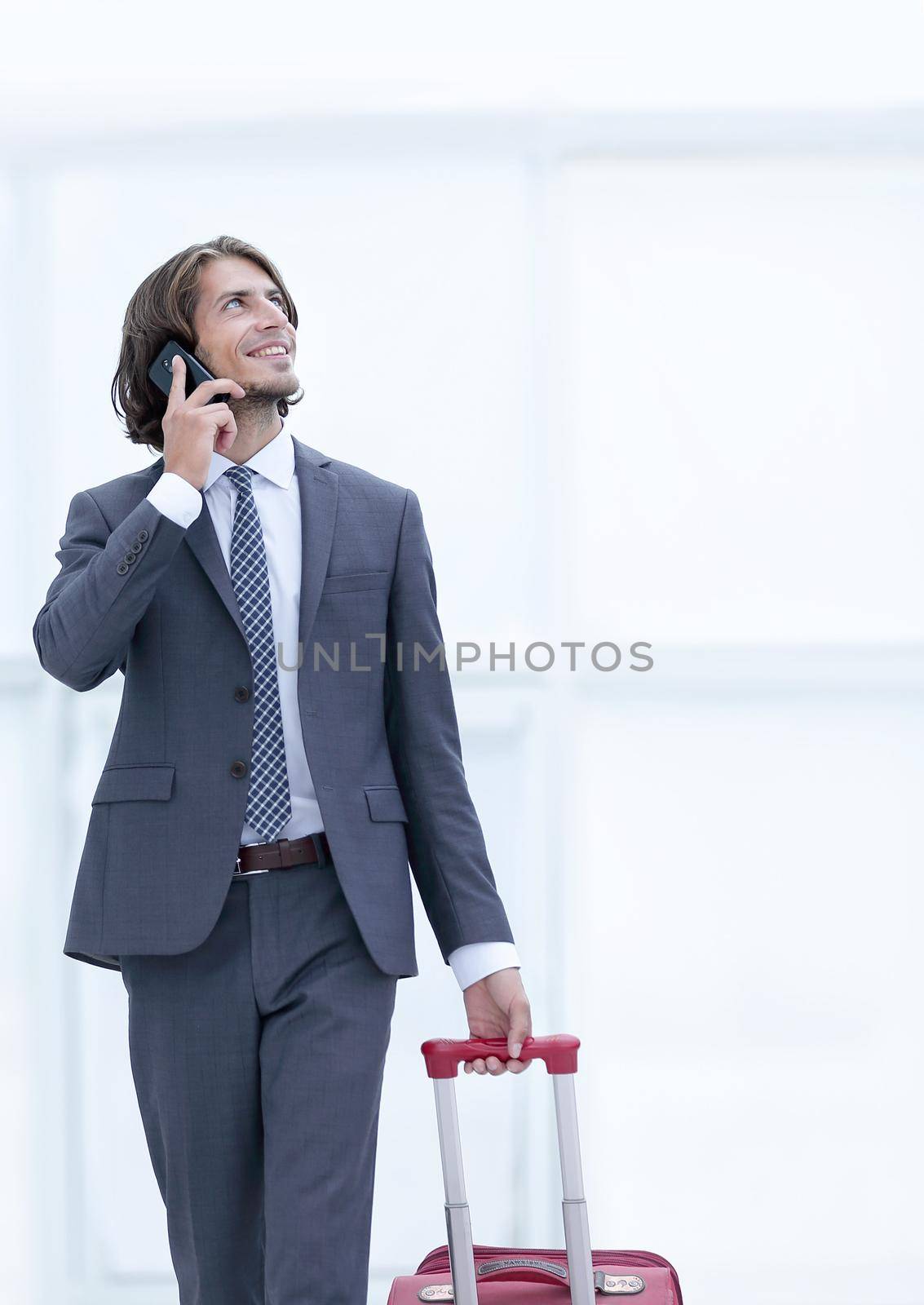 successful businessman with travel suitcase talking on the phone. photo with copy space