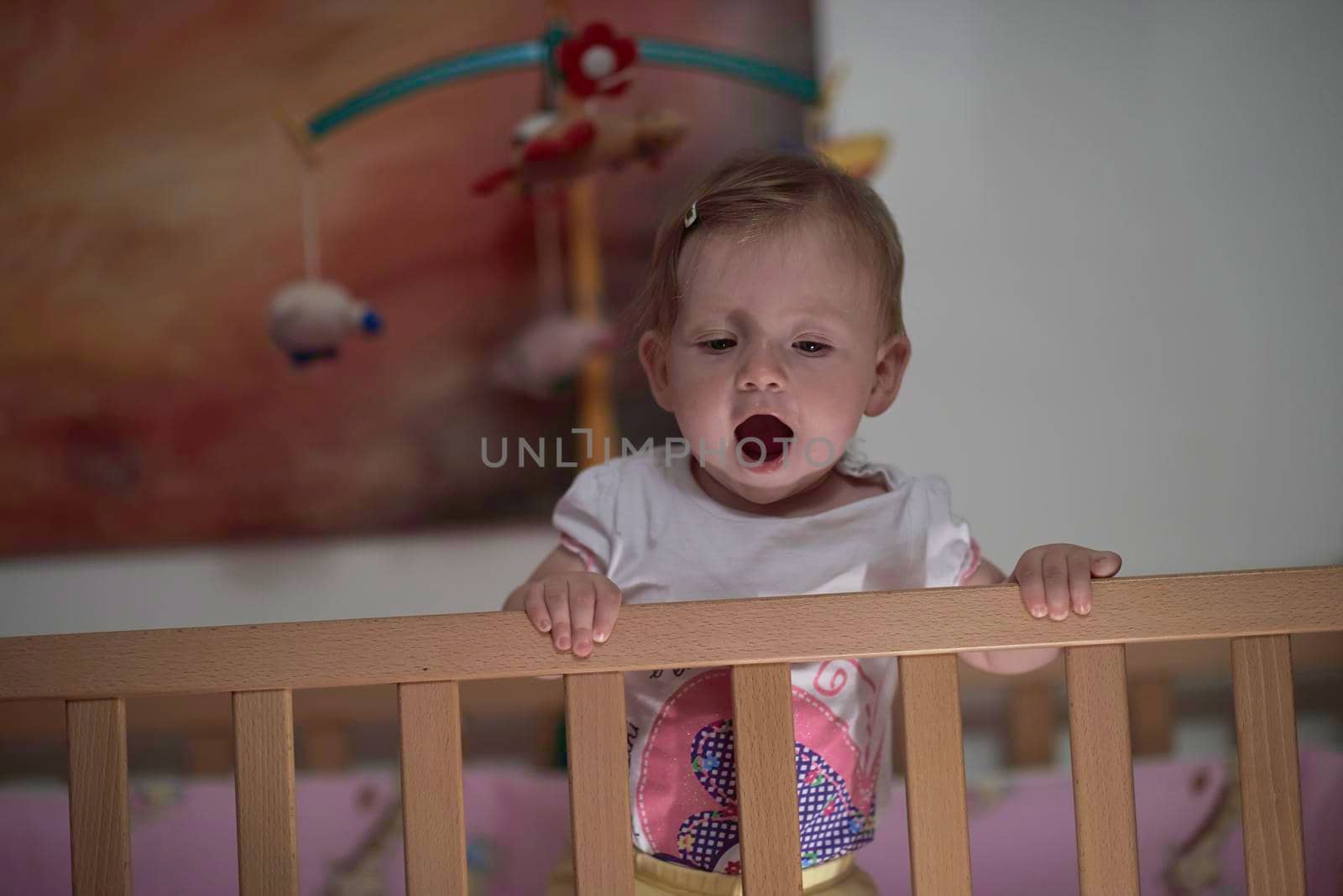 cute  little one year old baby playing with toys in bed while making first steps and learnig to walk