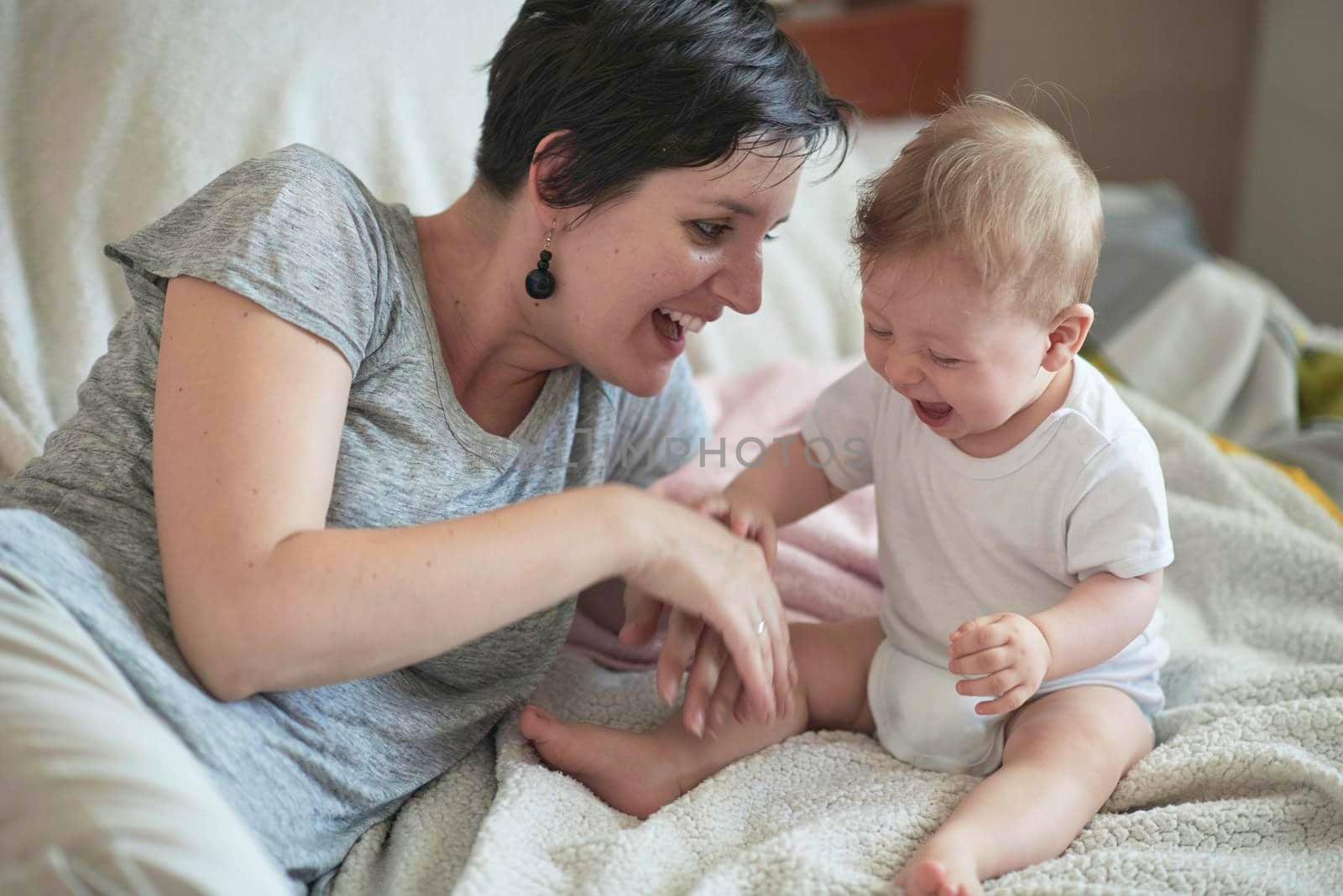 mother is playing with newborn baby at home