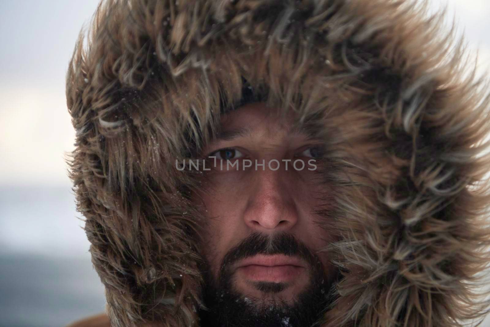 man at winter in stormy weather wearing warm  fur jacket by dotshock