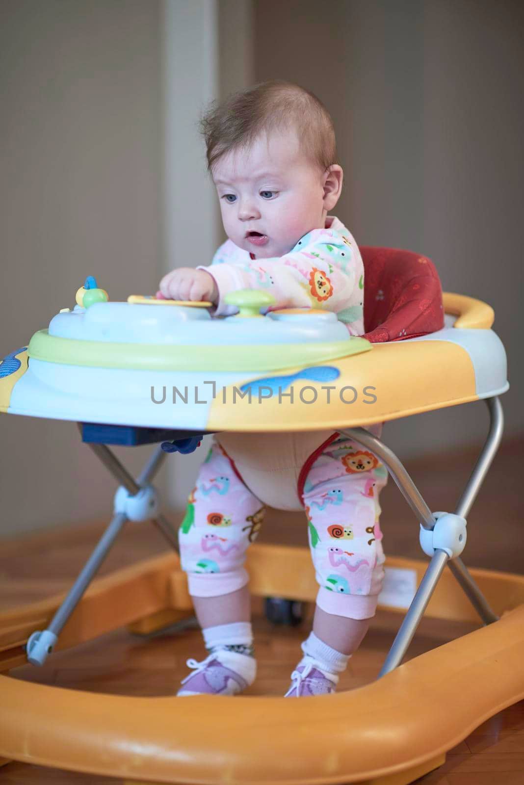 cute little baby learning to walk in walker at home