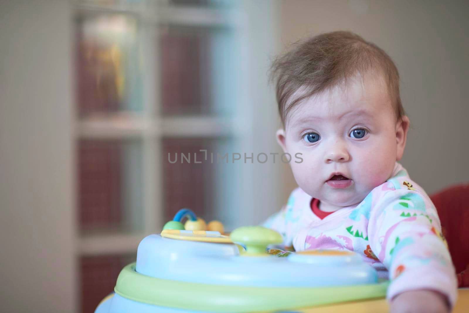 cute little baby learning to walk in walker at home