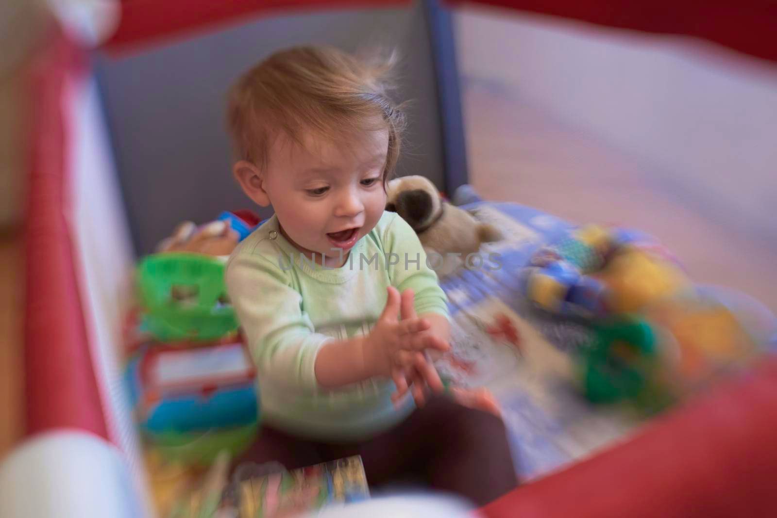 cute  little baby playing with toys in mobile bed making first steps and learnig to stand  and walk