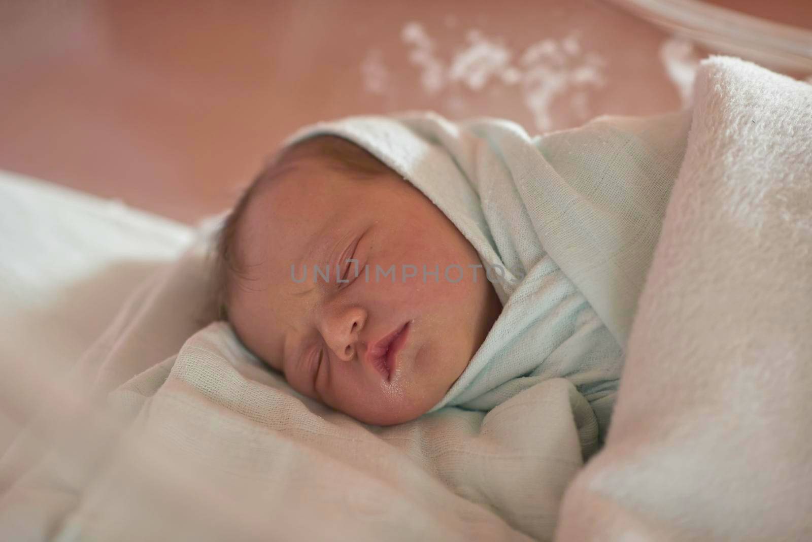 newborn baby child sleeping in plastic bed at hospital  wearing blanket coat