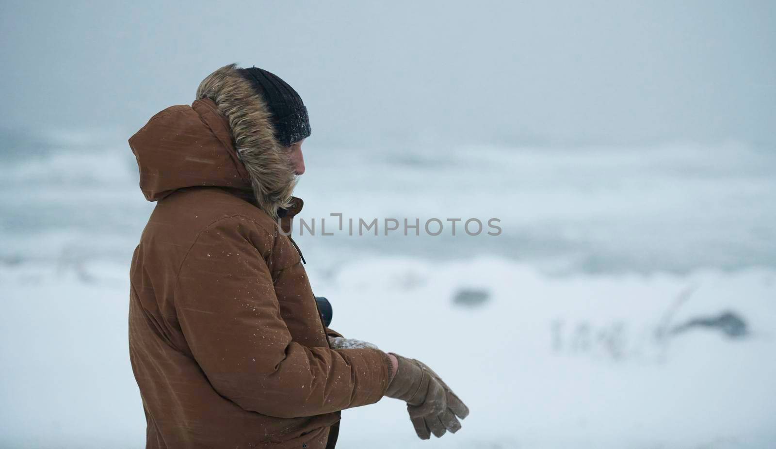 portrait local authentic eskimo  man at winter in stormy weather wearing warm  fur jacket