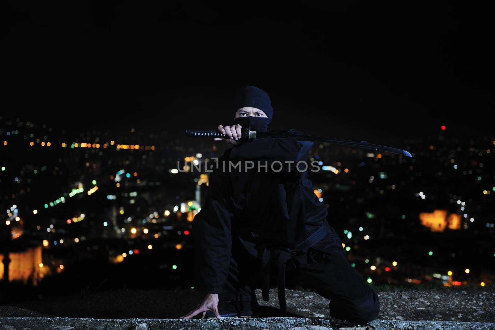 ninja assasin hold katana samurai old martial weapon swordat night with city lights in background
