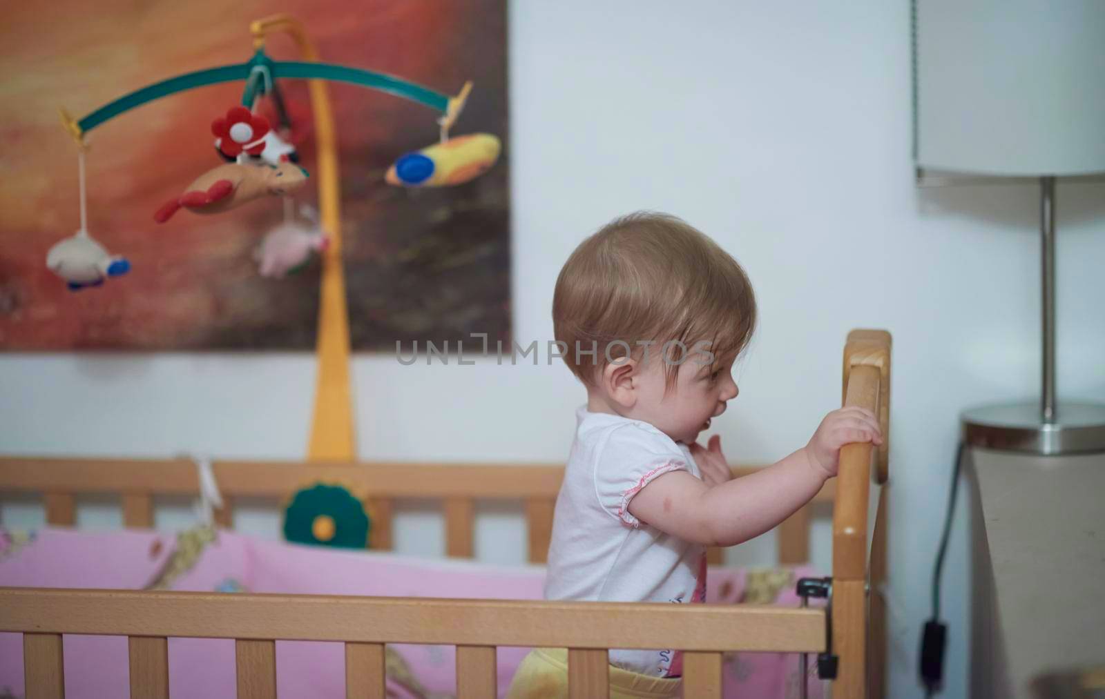 cute  little one year old baby playing with toys in bed while making first steps and learnig to walk