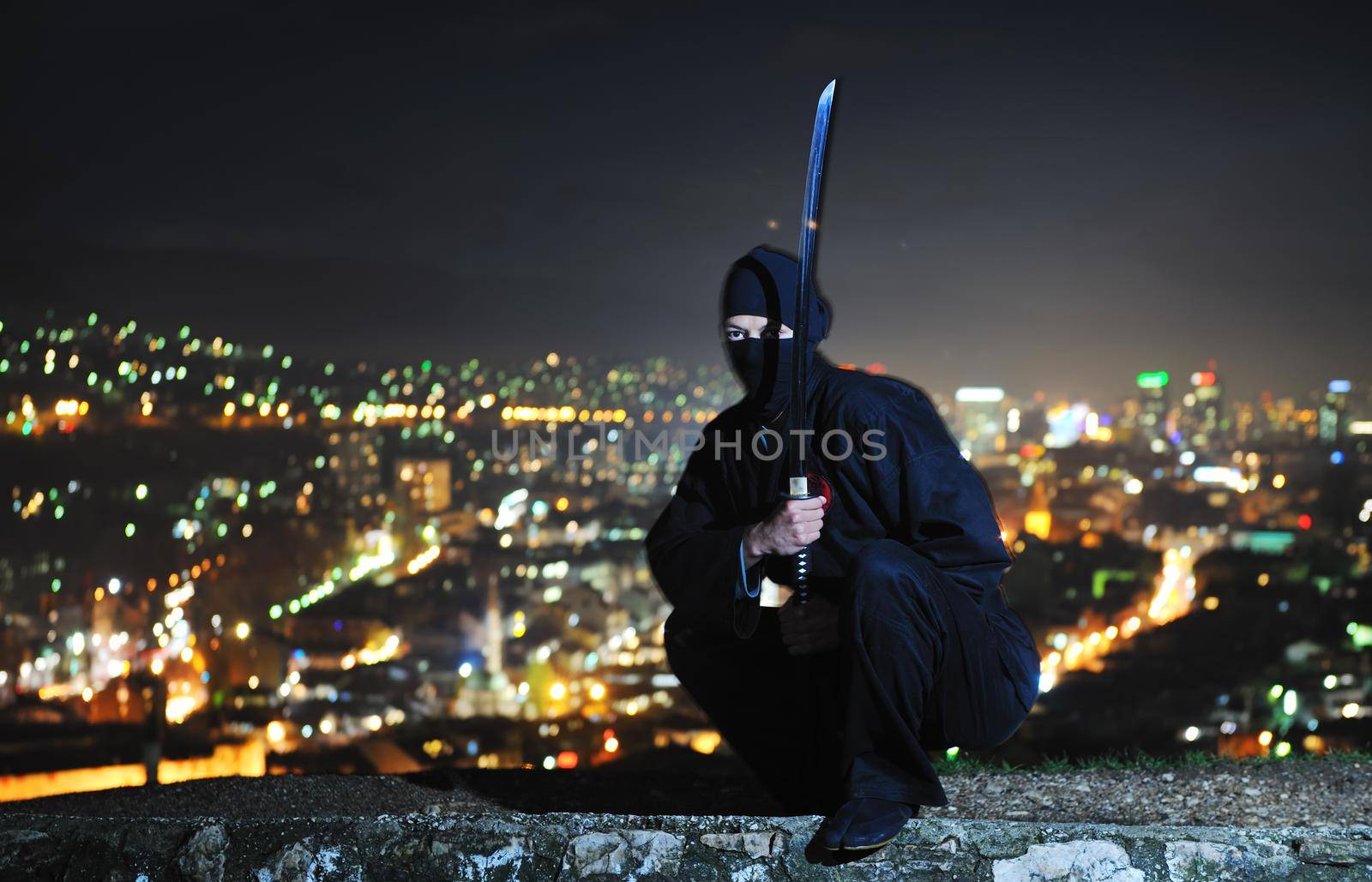 ninja assasin hold katana samurai old martial weapon swordat night with city lights in background