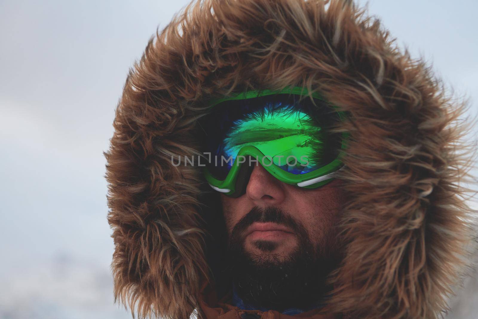 portrait local authentic eskimo  man at winter in stormy weather wearing warm  fur jacket