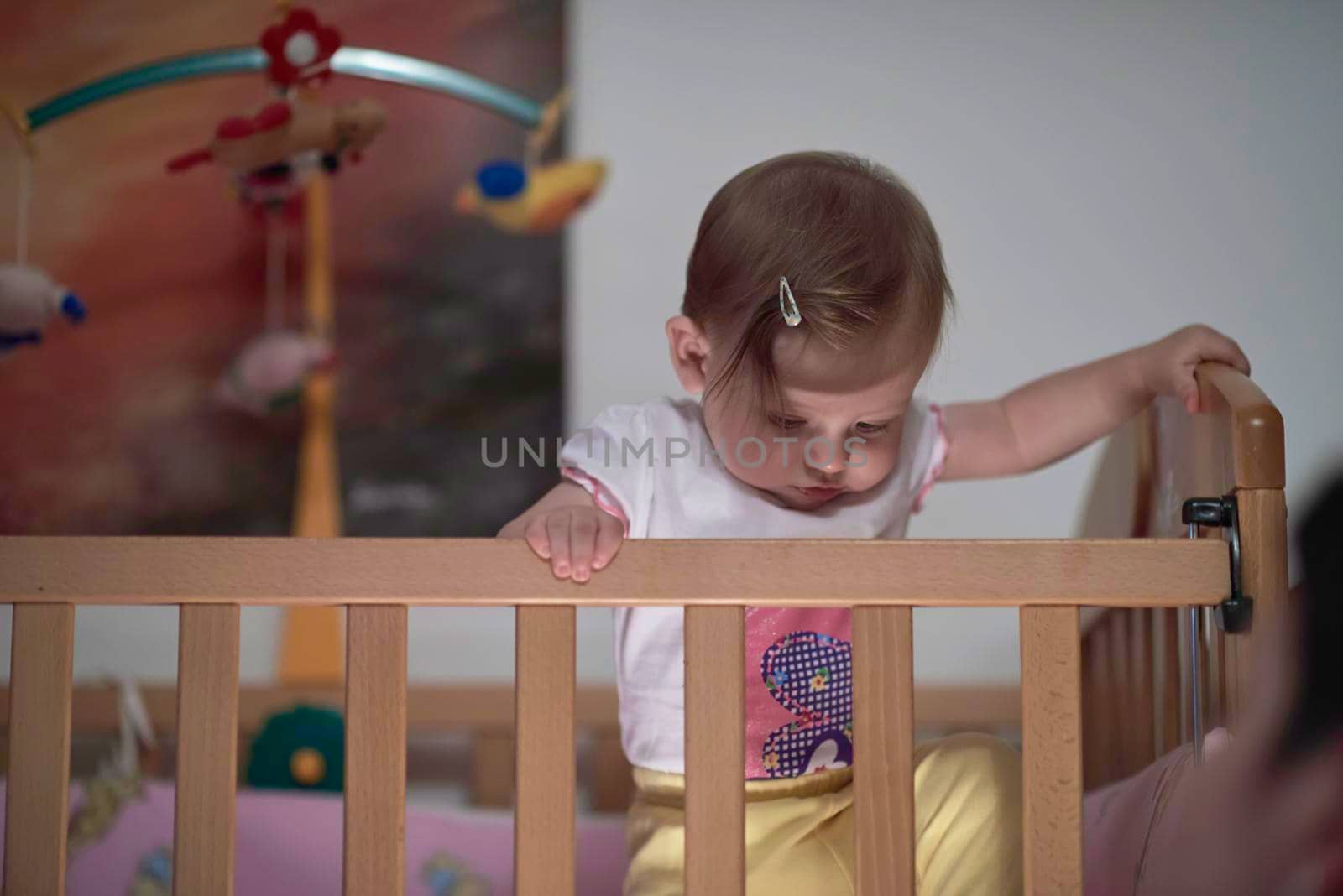 cute  little one year old baby playing with toys in bed while making first steps and learnig to walk