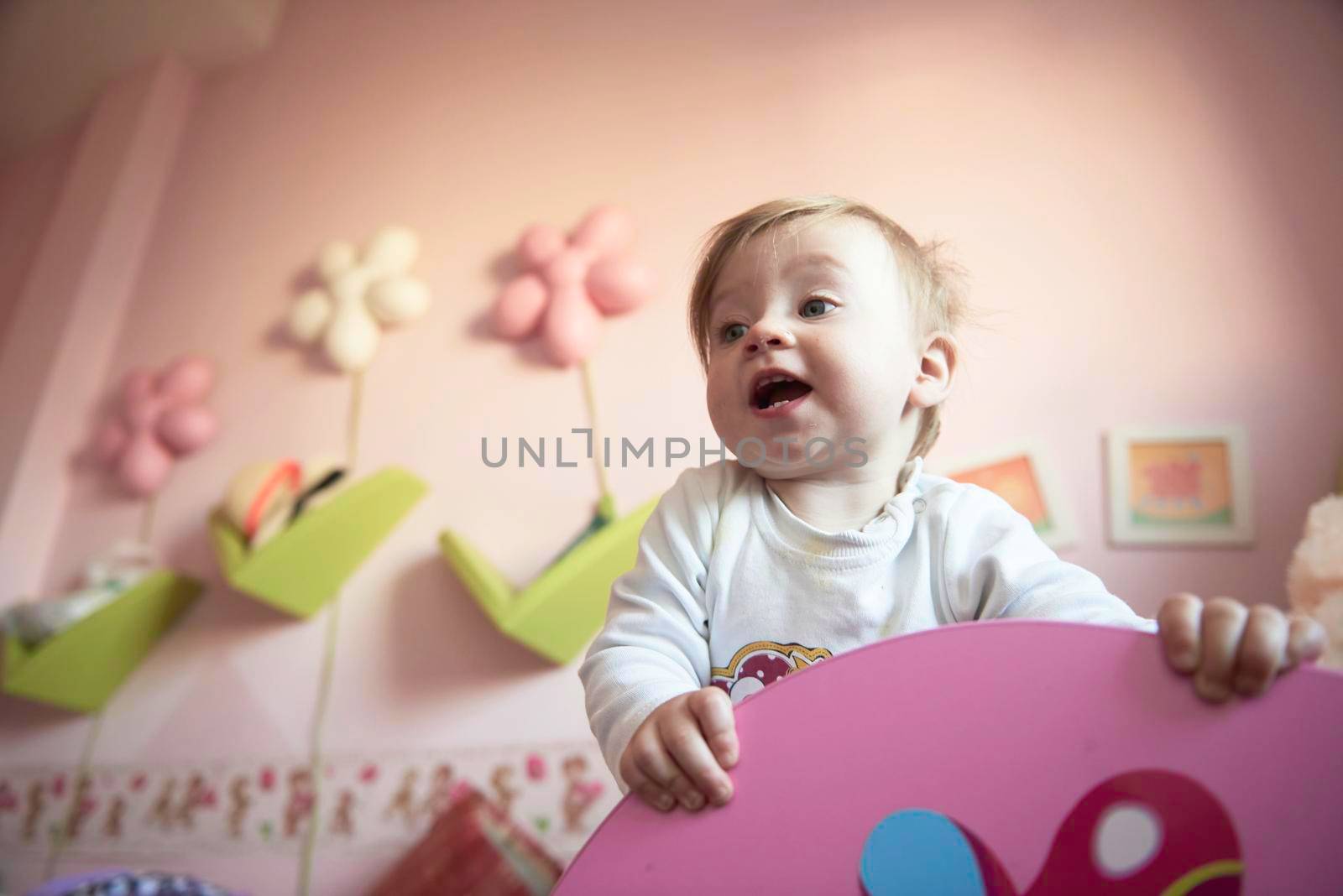 cute  little one year old baby playing  with toys at home while making first steps and learnig to walk