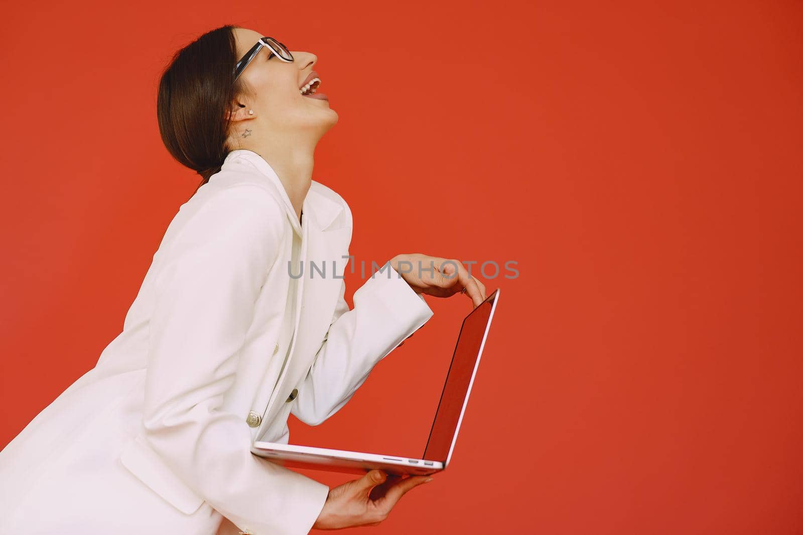 Woman in a studio. Lady with a laptop. Brunette in a white suit.