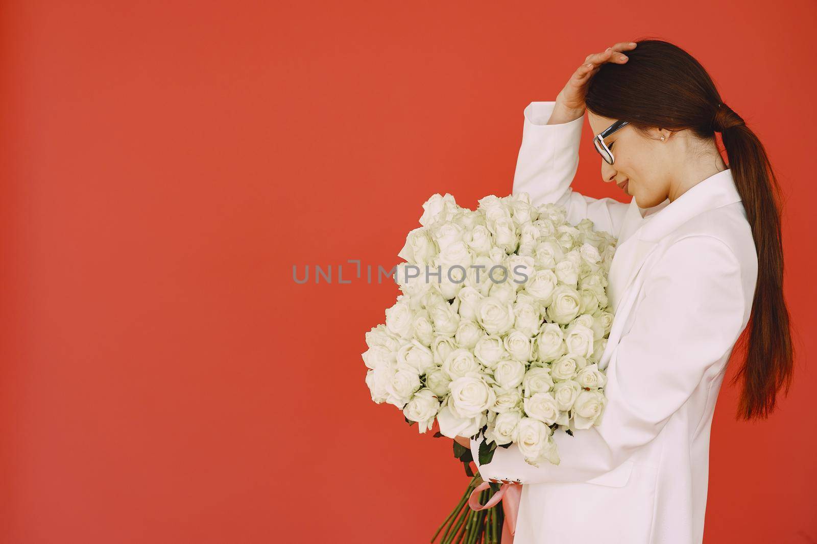 Beautiful girl in a studio. Stylish girl on a brown background. Lady with bouquet of white roses.