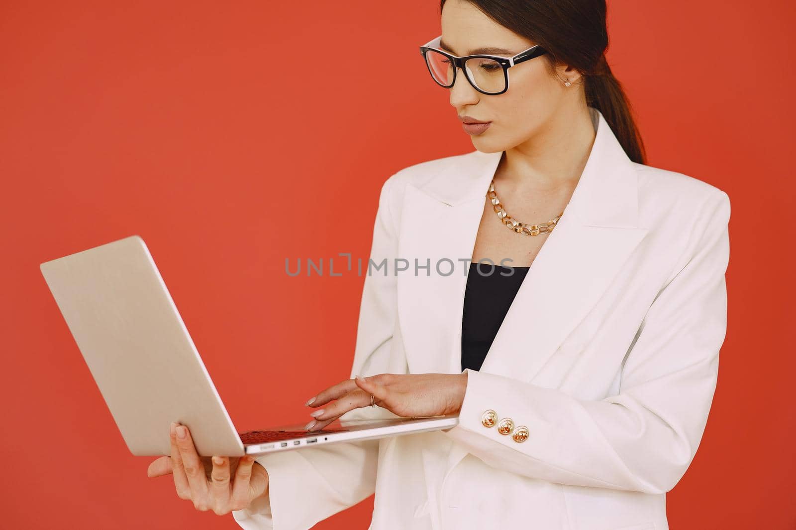 Woman in a studio. Lady with a laptop. Brunette in a white suit.