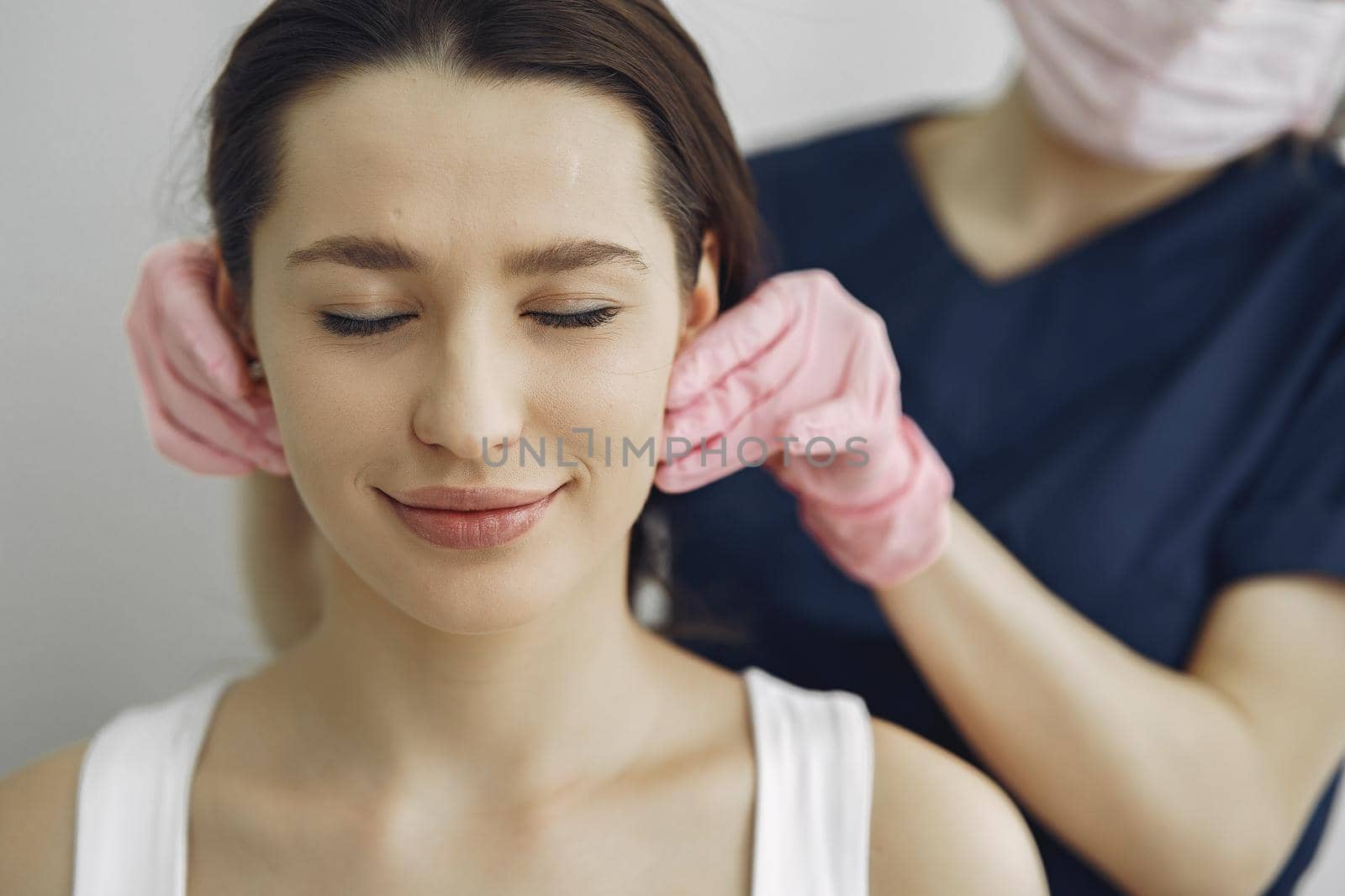 Cosmetologist holds hands near client's face. Woman with cosmetologist. Lady in a beauty studio.