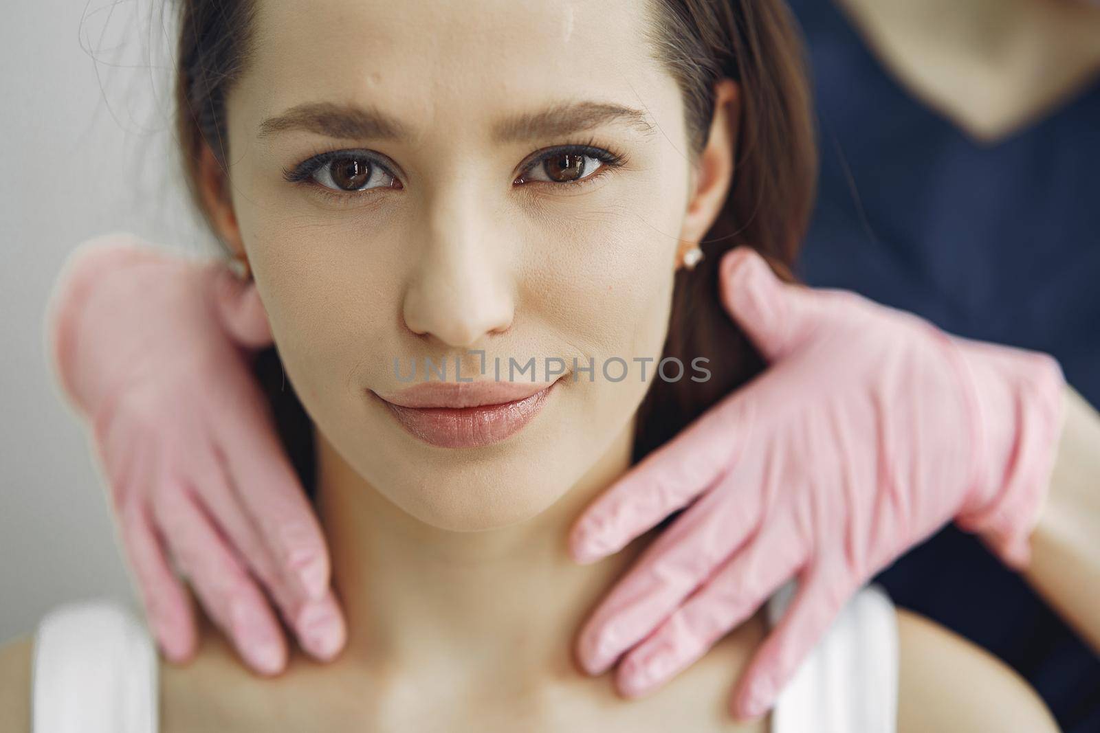 Cosmetologist holds hands near client's face. Woman with cosmetologist. Lady in a beauty studio.