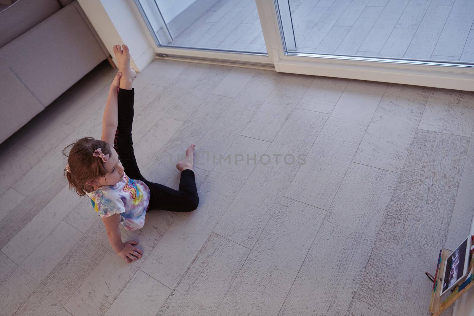 Little girl have online training over  tablet and doing modern ballet dance exercise at home. Online education concept class in modern ballet school. Social distance during quarantine, self-isolation in coronavirus