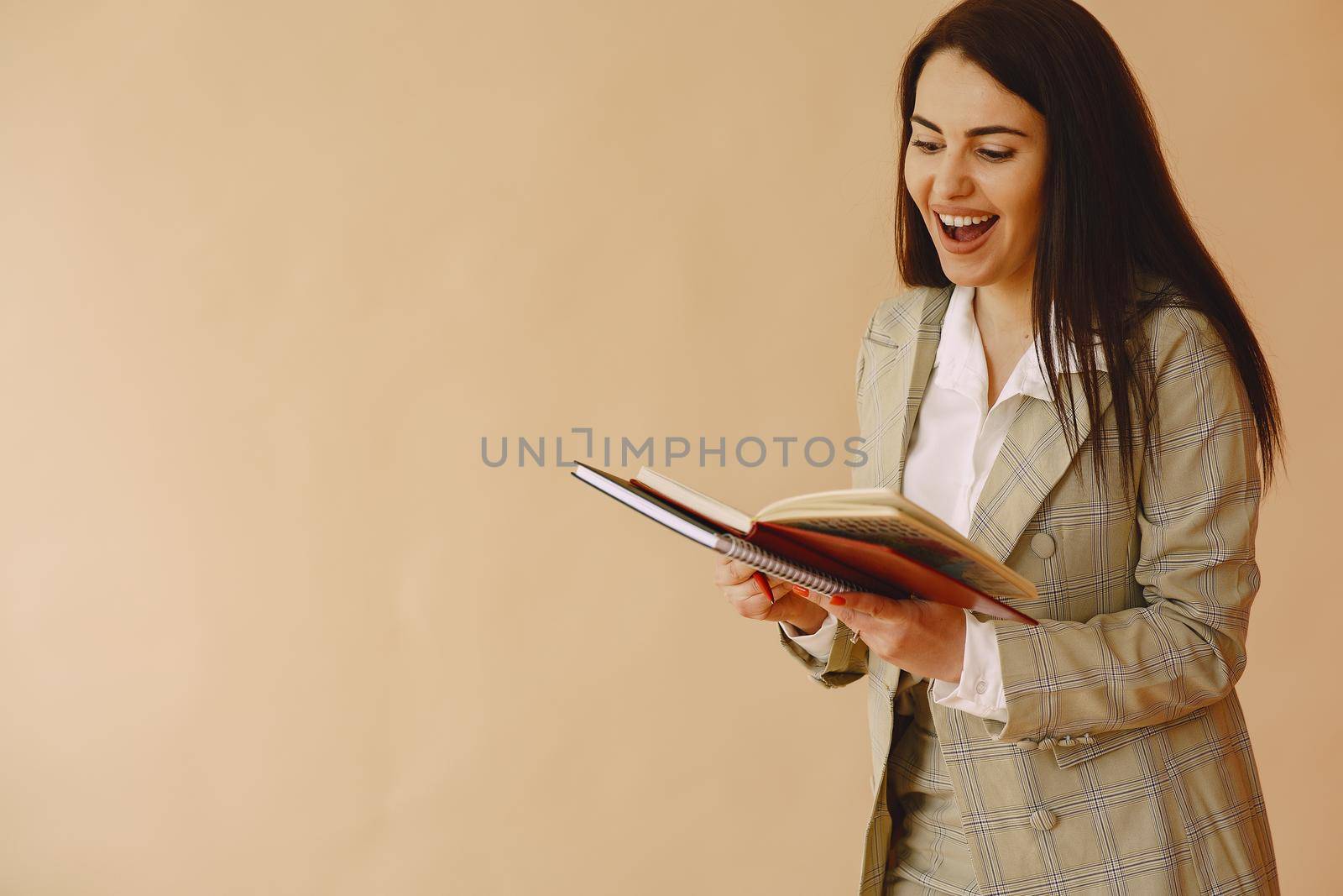 Woman in a studio. Lady with a notebook. Brunette in a brown jacket.
