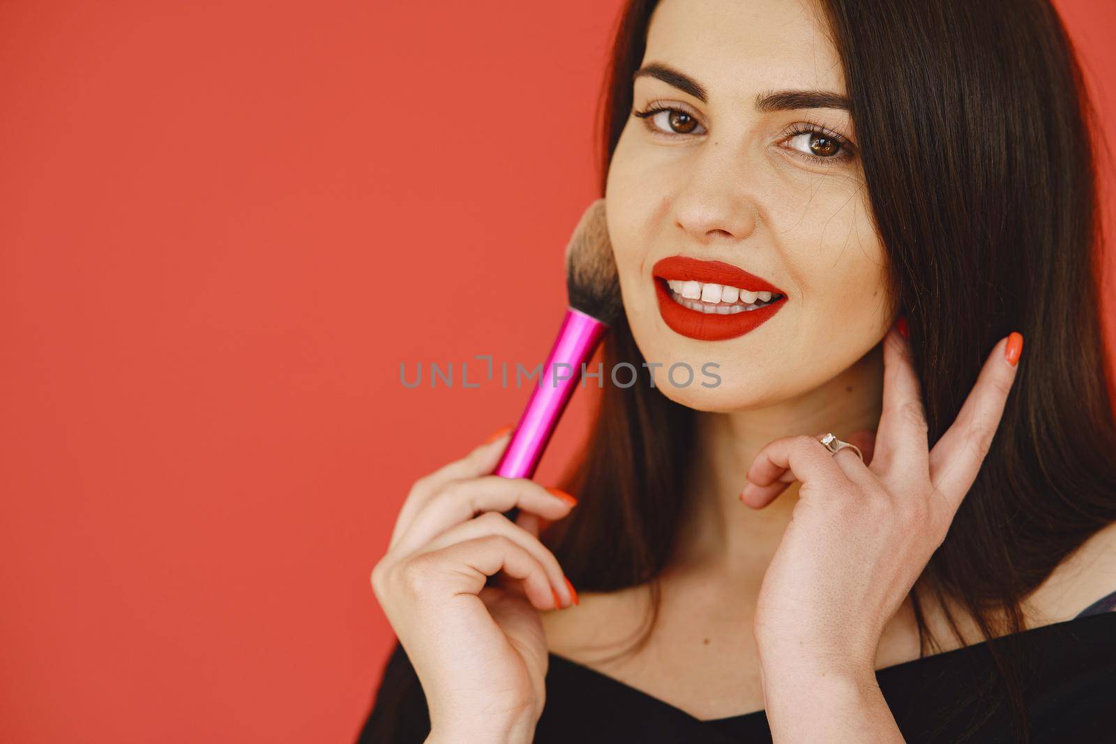 Woman with brush for make up. Girl on a red background.