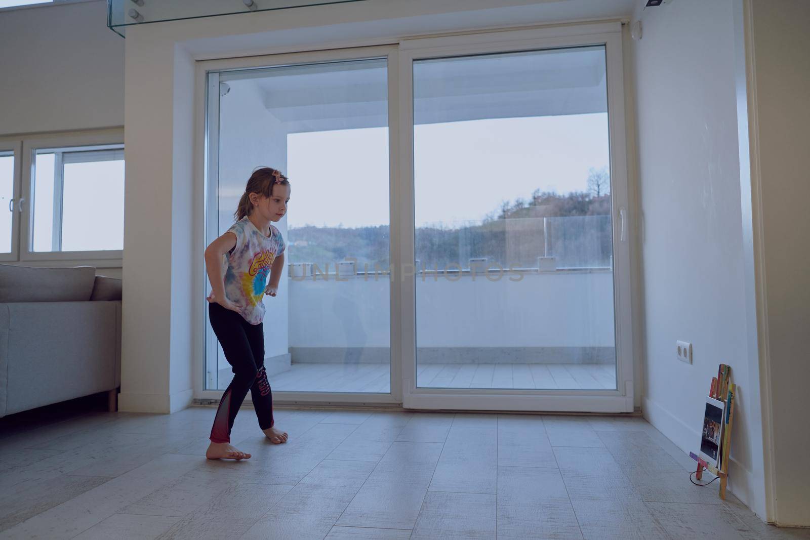 Little girl have online training over  tablet and doing modern ballet dance exercise at home. Online education concept class in modern ballet school. Social distance during quarantine, self-isolation in coronavirus