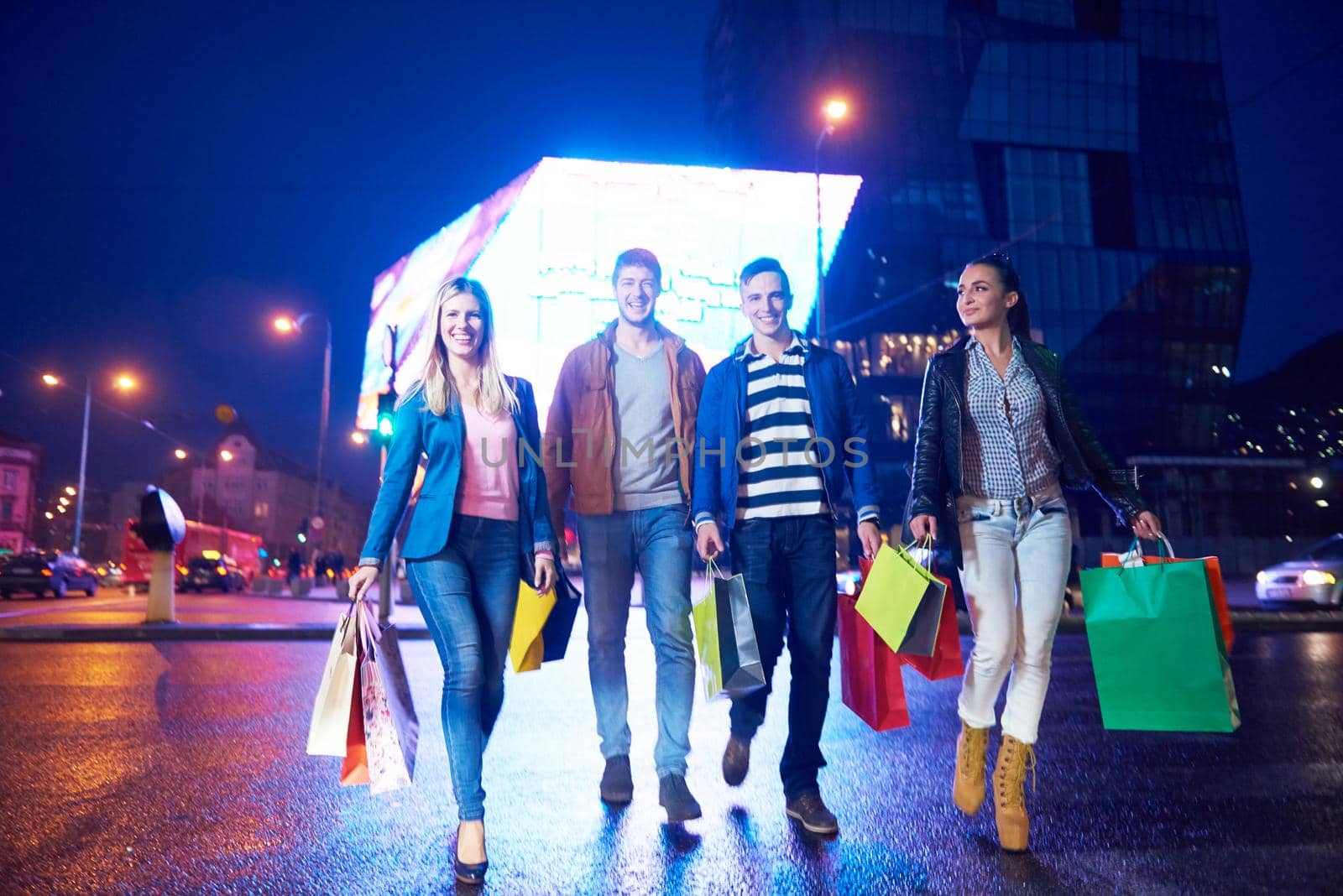 Group Of Friends Enjoying Shopping Trip Together
group of happy young frineds enjoying shopping night and walking on steet on night in with mall in background