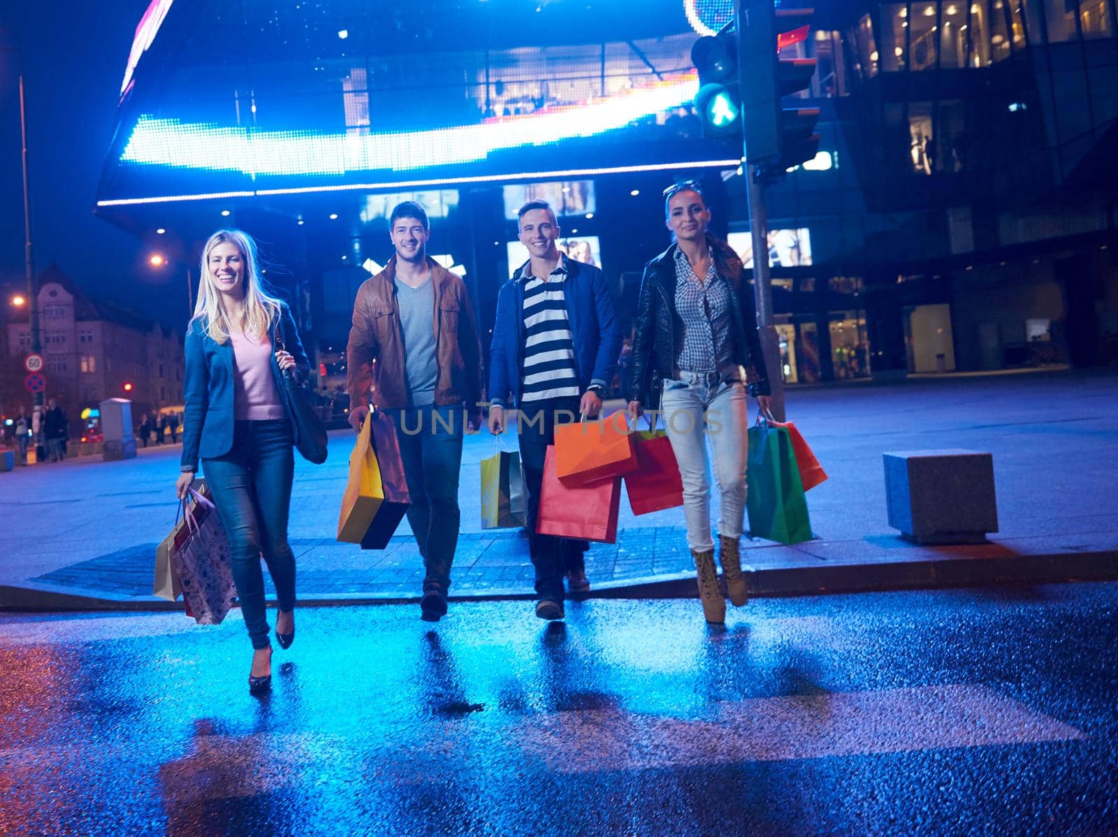 Group Of Friends Enjoying Shopping Trip Together
group of happy young frineds enjoying shopping night and walking on steet on night in with mall in background