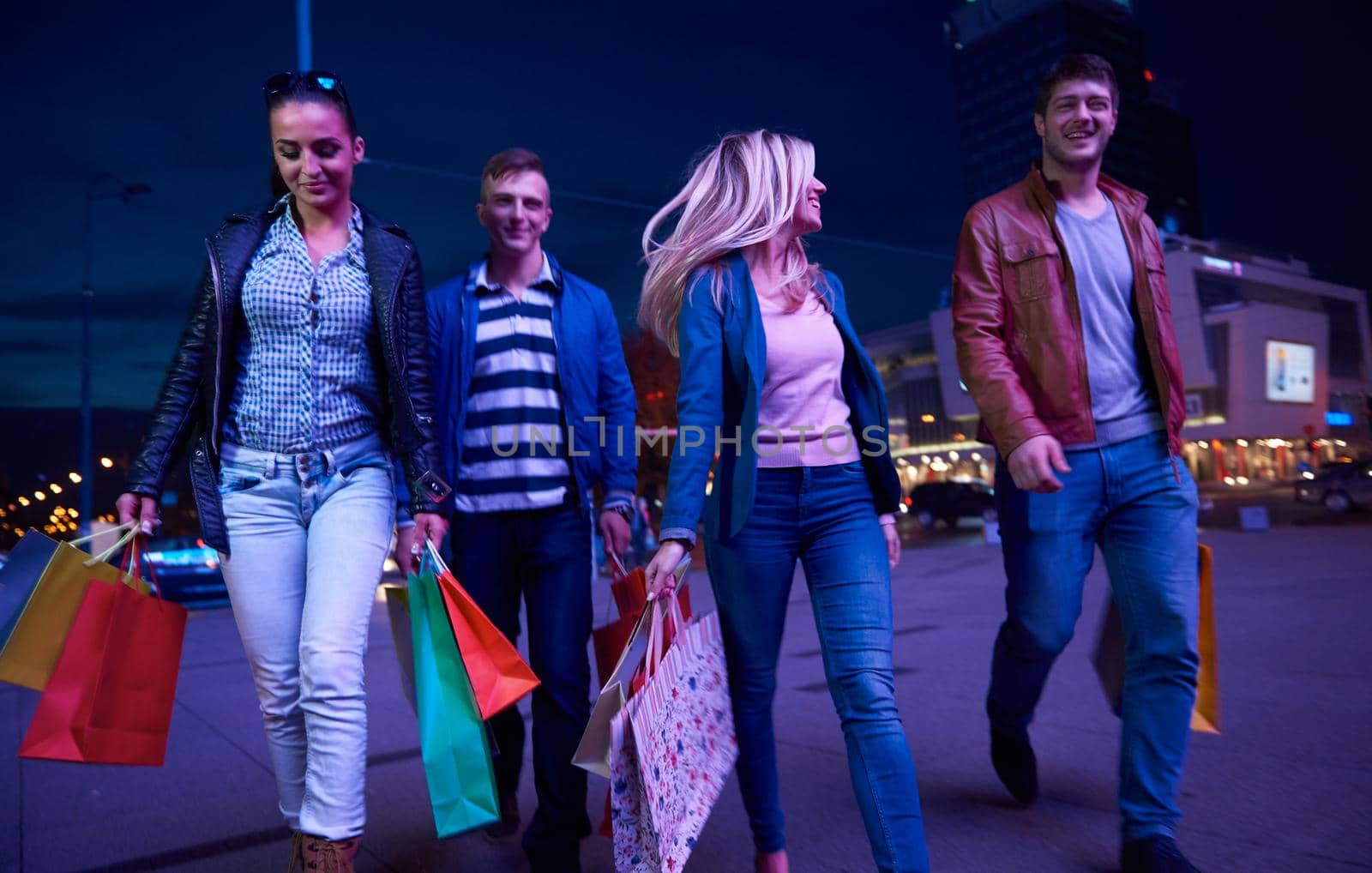 Group Of Friends Enjoying Shopping Trip Together
group of happy young frineds enjoying shopping night and walking on steet on night in with mall in background