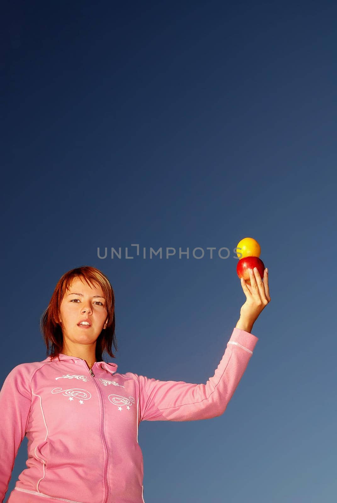 young woman balancing fruits in nature (healthy food and low calorie food concept)