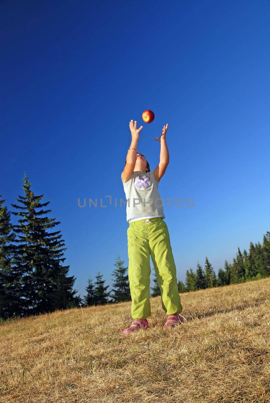 happy girl throwing apple outside by dotshock