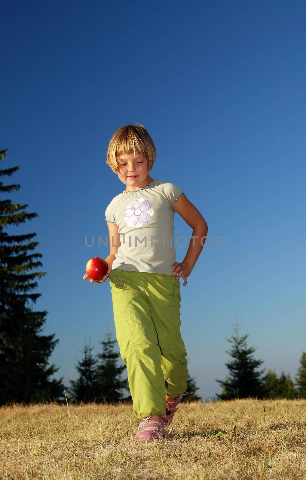 young girl balancing fruits in nature (healthy food and low calorie food concept)