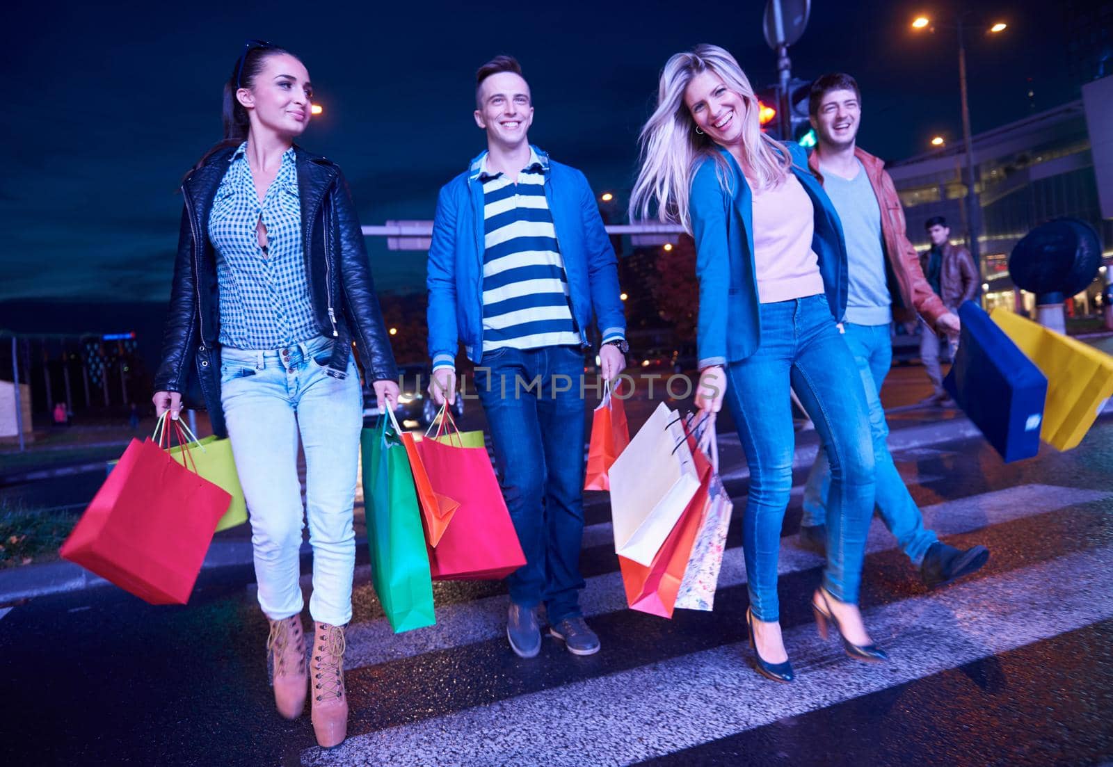 Group Of Friends Enjoying Shopping Trip Together
group of happy young frineds enjoying shopping night and walking on steet on night in with mall in background