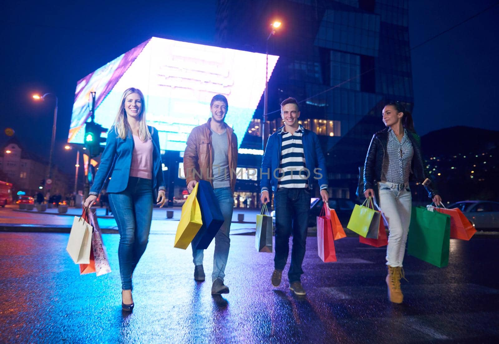 Group Of Friends Enjoying Shopping Trip Together
group of happy young frineds enjoying shopping night and walking on steet on night in with mall in background
