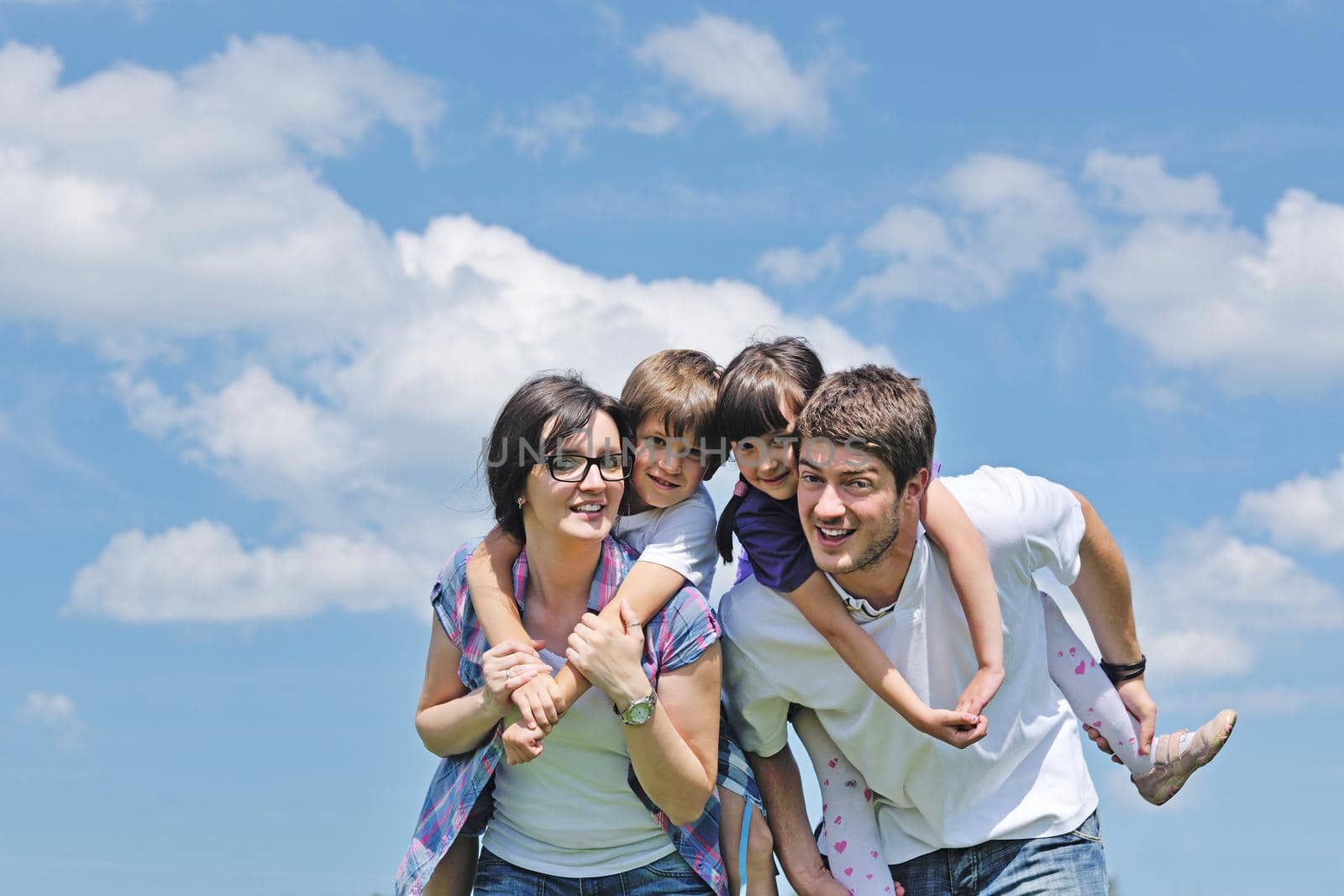 happy young family with their kids have fun and relax outdoors in nature with blue sky in background