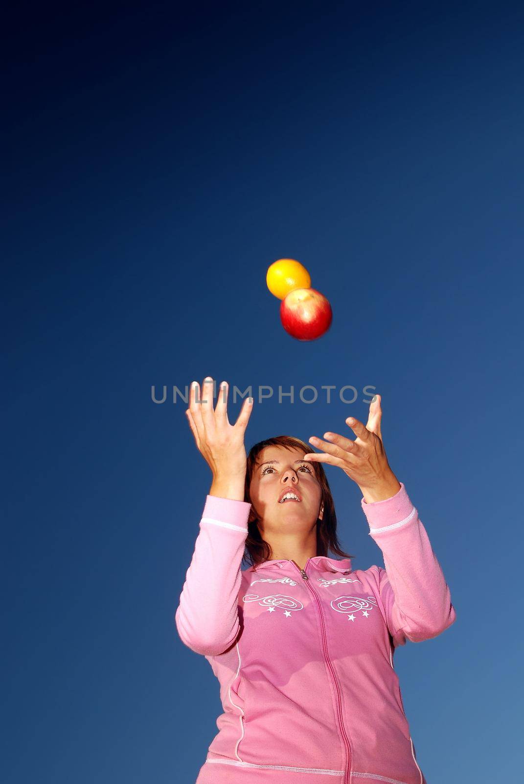 young woman balancing fruits in nature (healthy food and low calorie food concept)