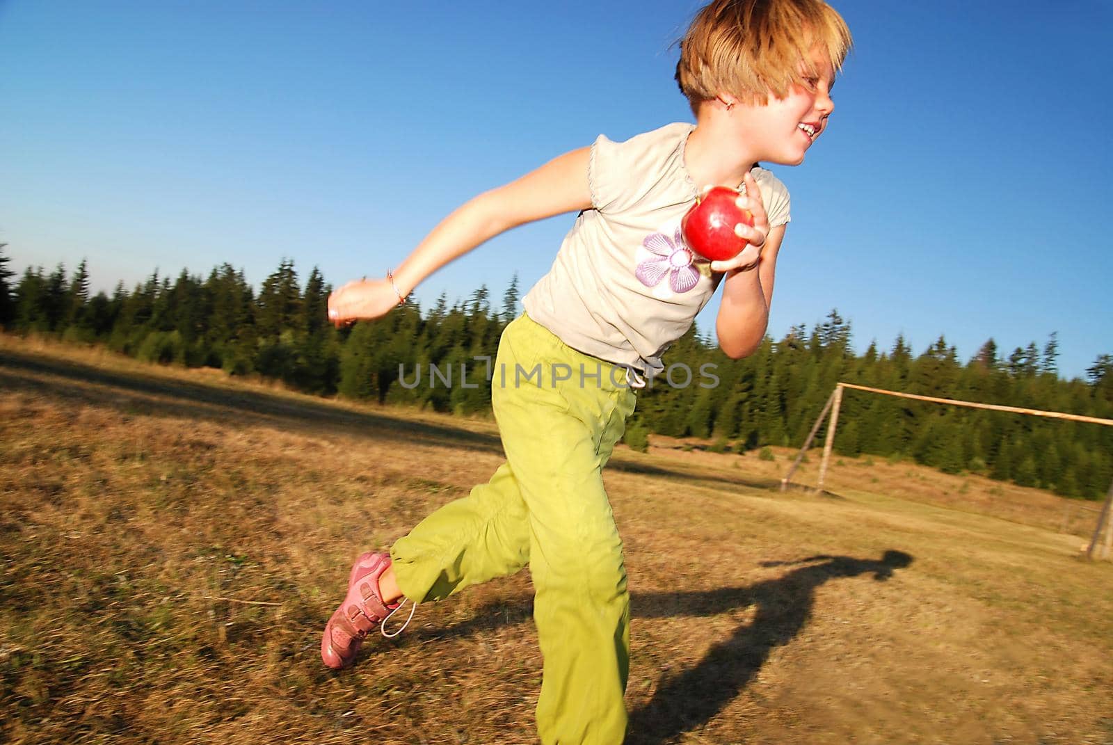 young girl with apple running in field