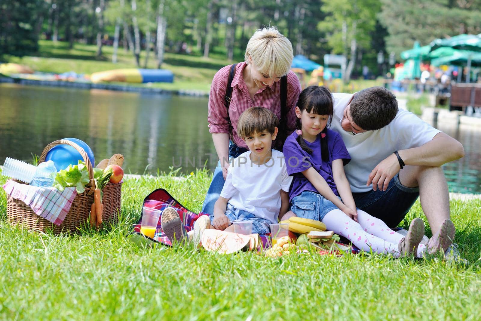 Happy young  family playing together with kids and eat healthy food  in a picnic outdoors