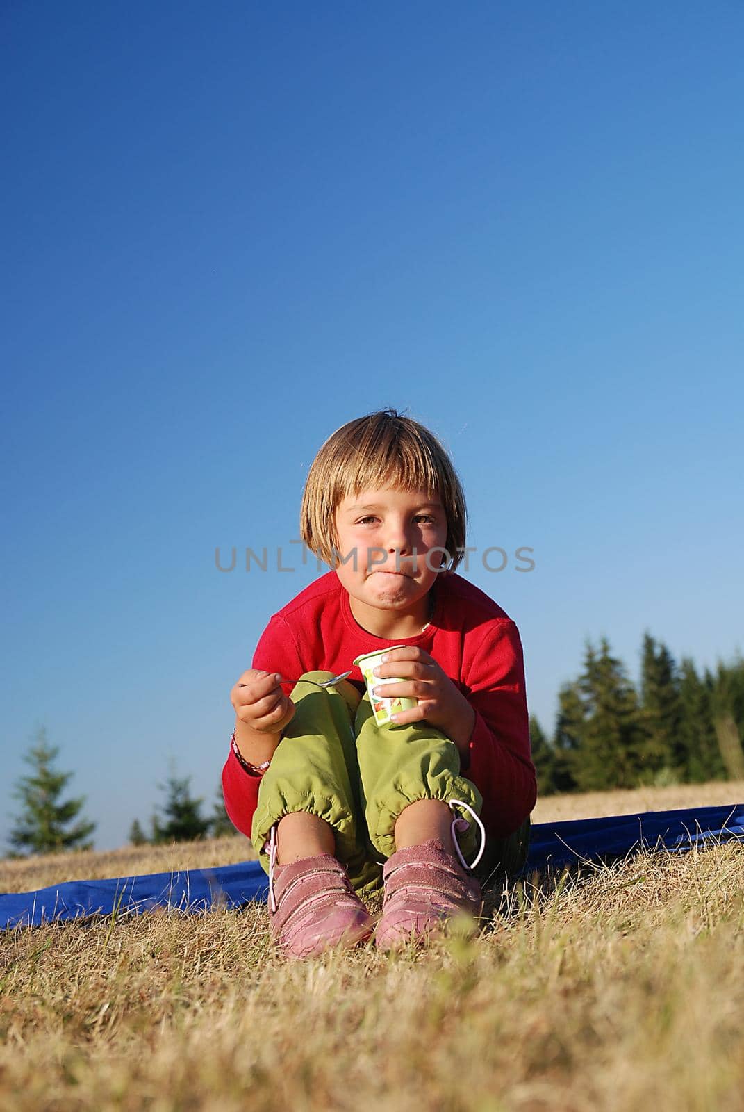 happy llittle girl eating healthy food in nature