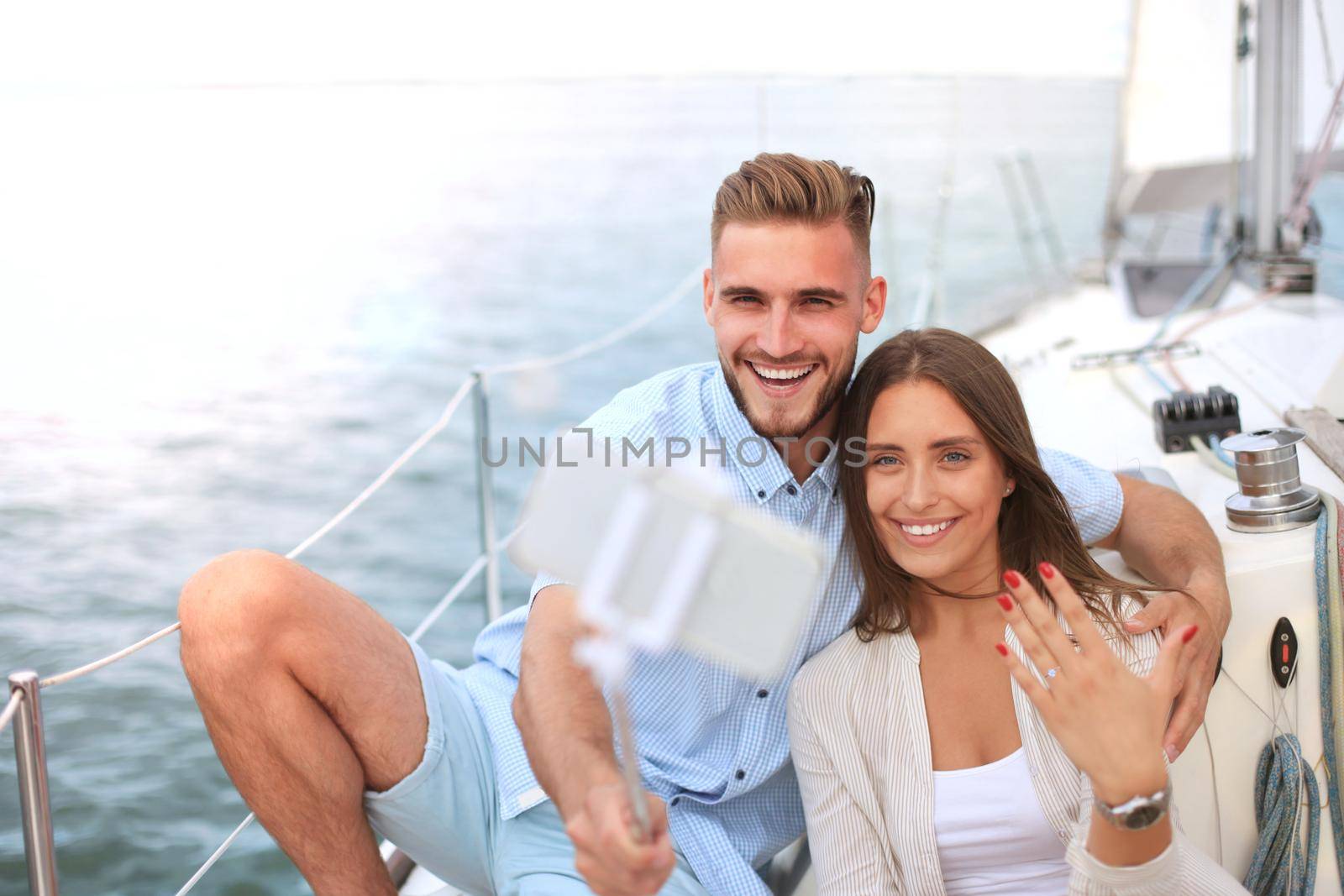 Happy couple taking a selfie after engagement proposal at sailing boat, relaxing on a yacht at the sea. by tsyhun